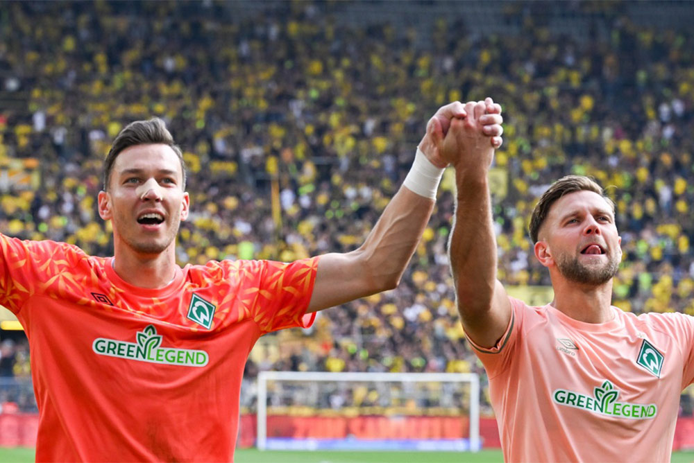 Werder Bremen Spieler feiern mit den Fans nach einem wichtigen Sieg.